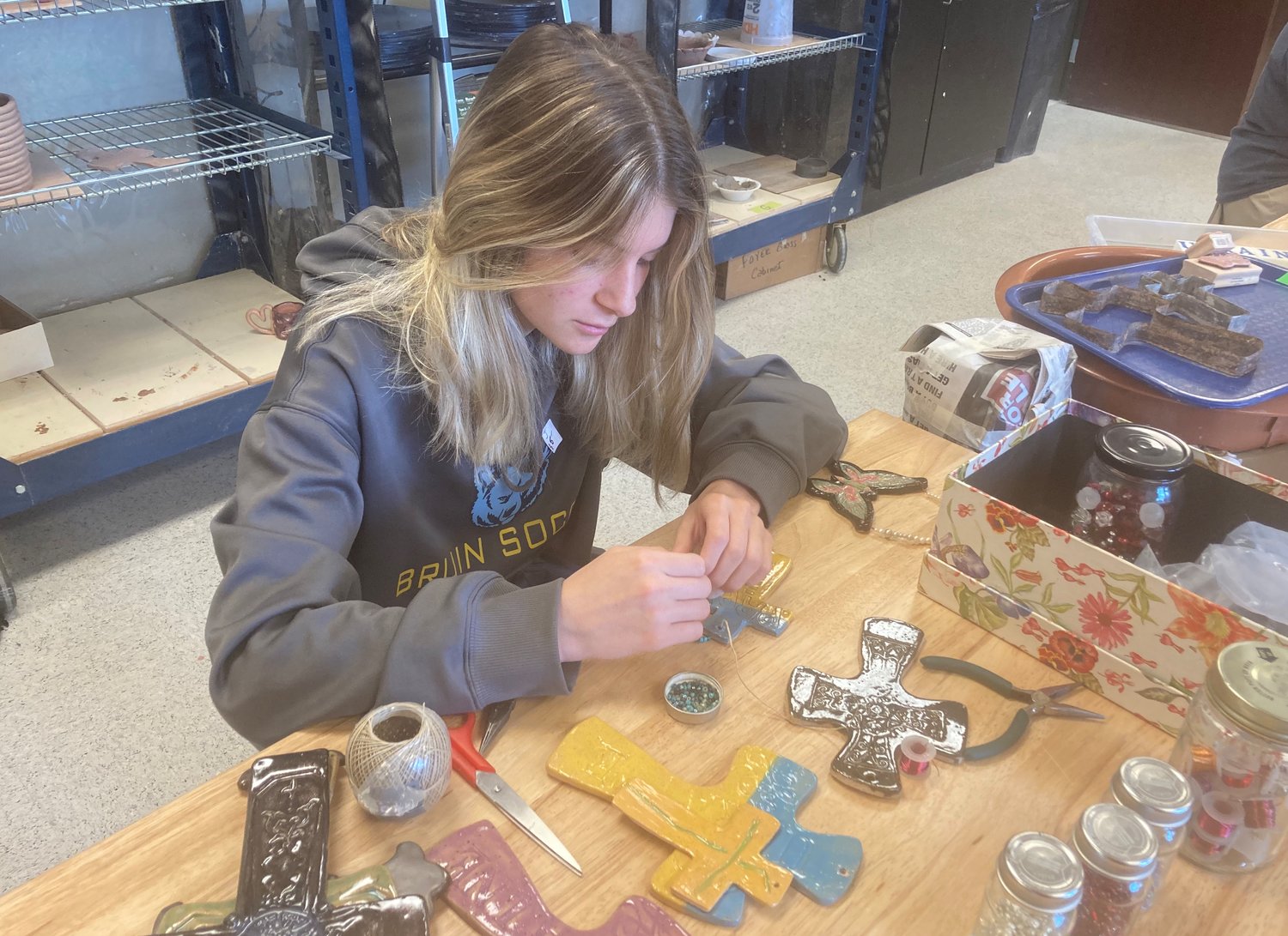 St. Joseph Catholic School art student Truus Alford decorates a student-made ceramic cross to honor Ukraine in the wake of Russia’s invasion of the Eastern European country. The crosses are selling for $5 for small ones and $10 for large ones.